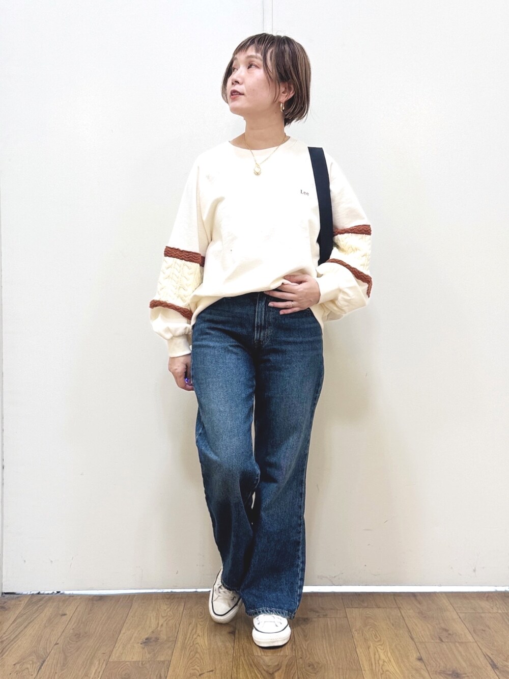 ブルー系のデニムパンツ、ホワイト系のスウェット、ブラック系のショルダーバッグを着用したレディースの冬コーディネートの6枚目の写真