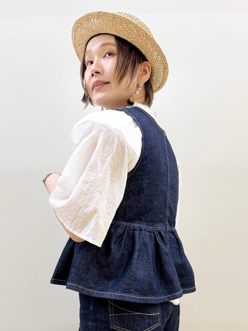 ブラック系のバレエシューズ、ゴールド系のかごバッグ、ブルー系のデニムパンツを着用したレディースの夏コーディネートの3枚目の写真