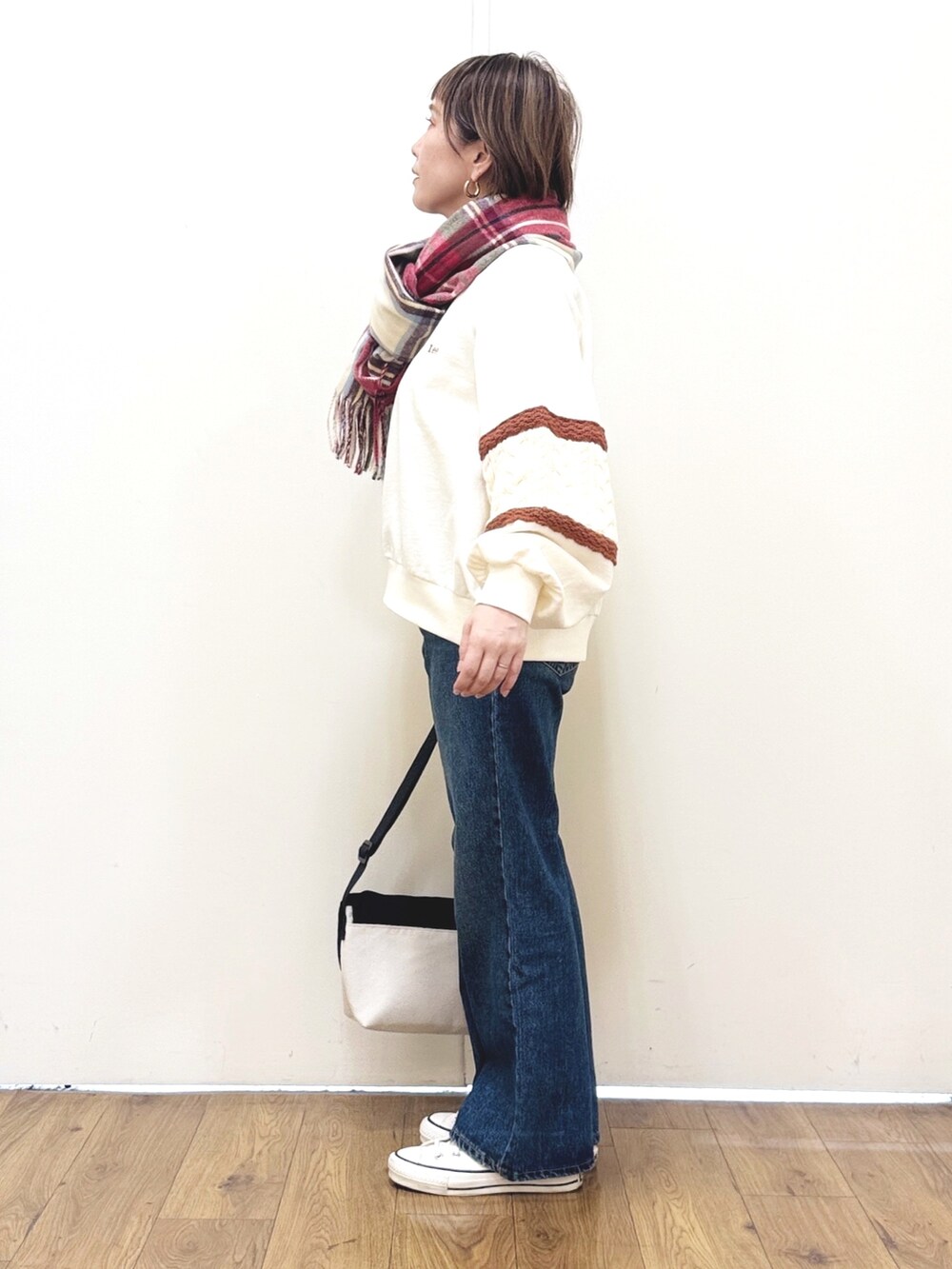 ブルー系のデニムパンツ、ホワイト系のスウェット、ブラック系のショルダーバッグを着用したレディースの冬コーディネートの3枚目の写真