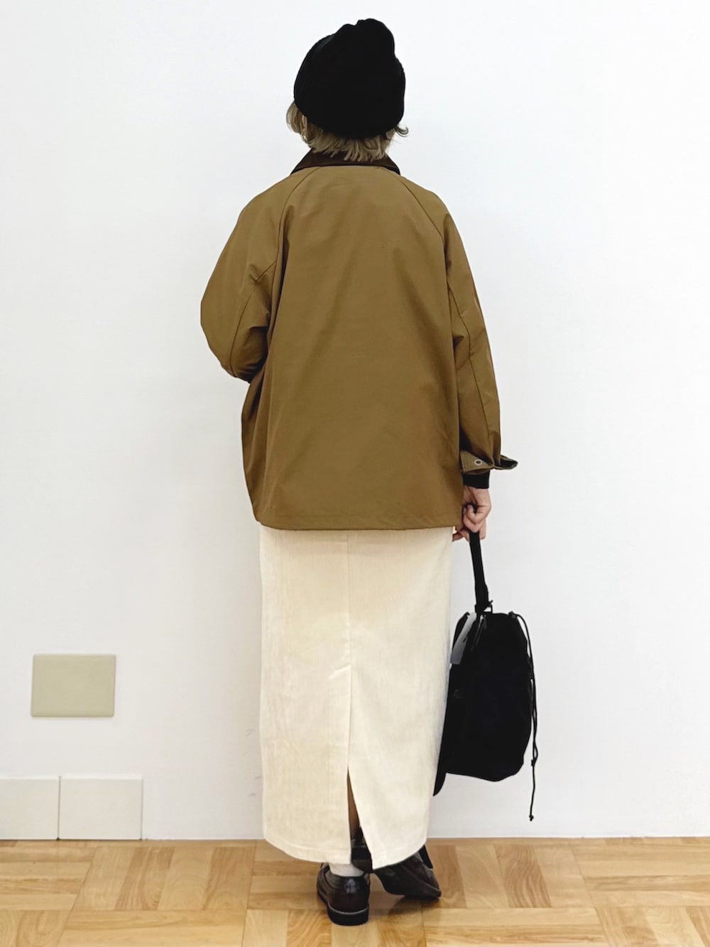 ブラック系のショルダーバッグ、ホワイト系のスカート、ブラック系のニット/セーターを着用したレディースの秋コーディネートの6枚目の写真