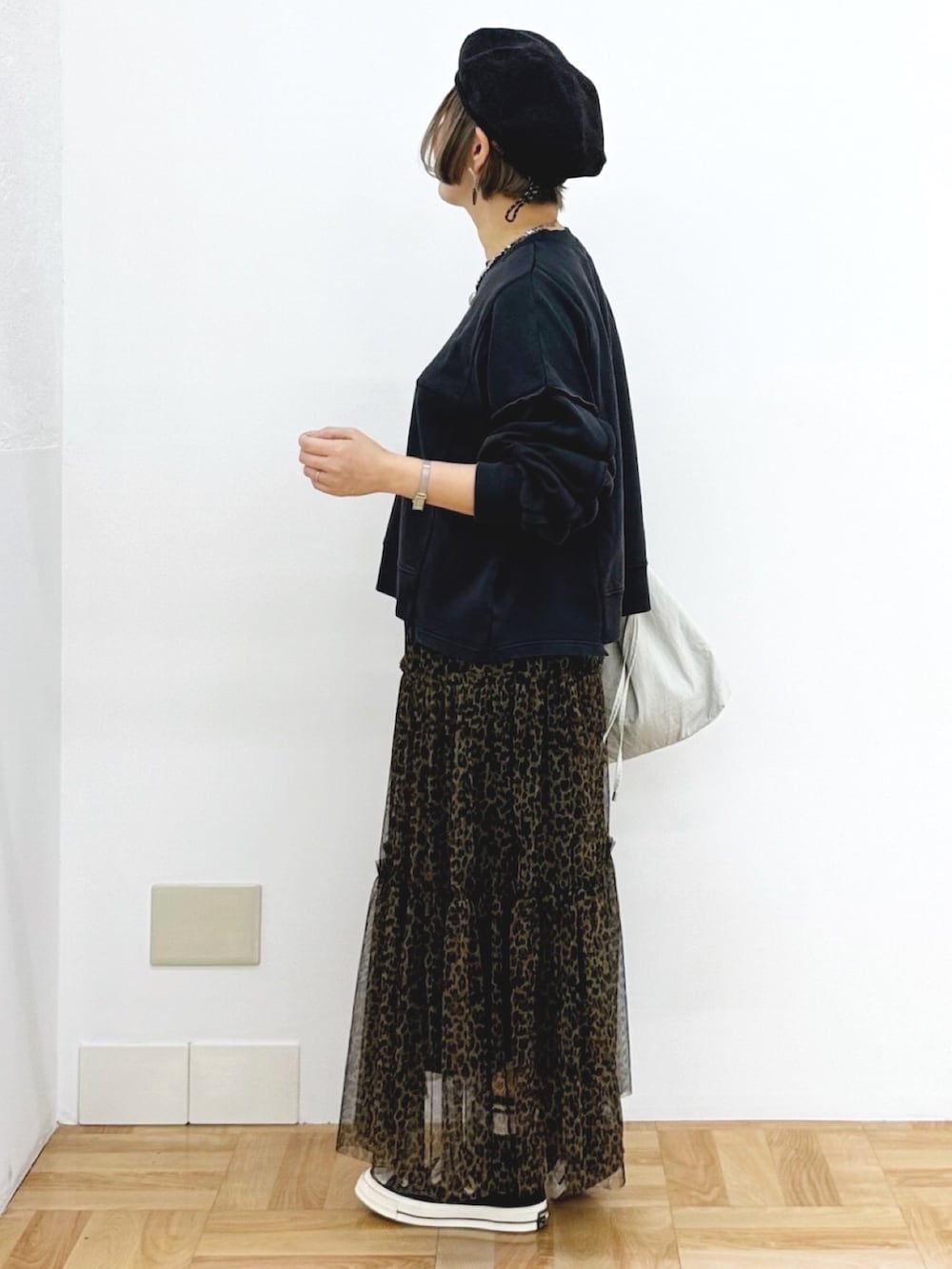 ブラック系のスウェット、ブラウン系のスカート、ホワイト系のショルダーバッグを着用したレディースの秋コーディネートの3枚目の写真