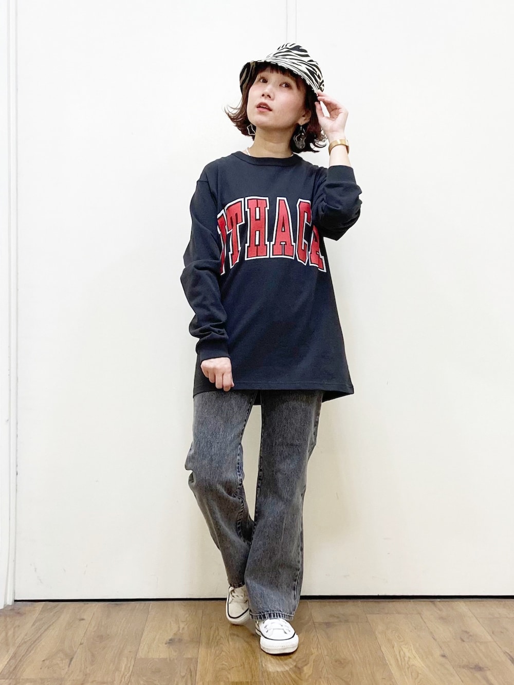 グレー系のTシャツ/カットソー、ブラック系のデニムパンツ、ホワイト系のスニーカーを着用したレディースの春コーディネートの2枚目の写真