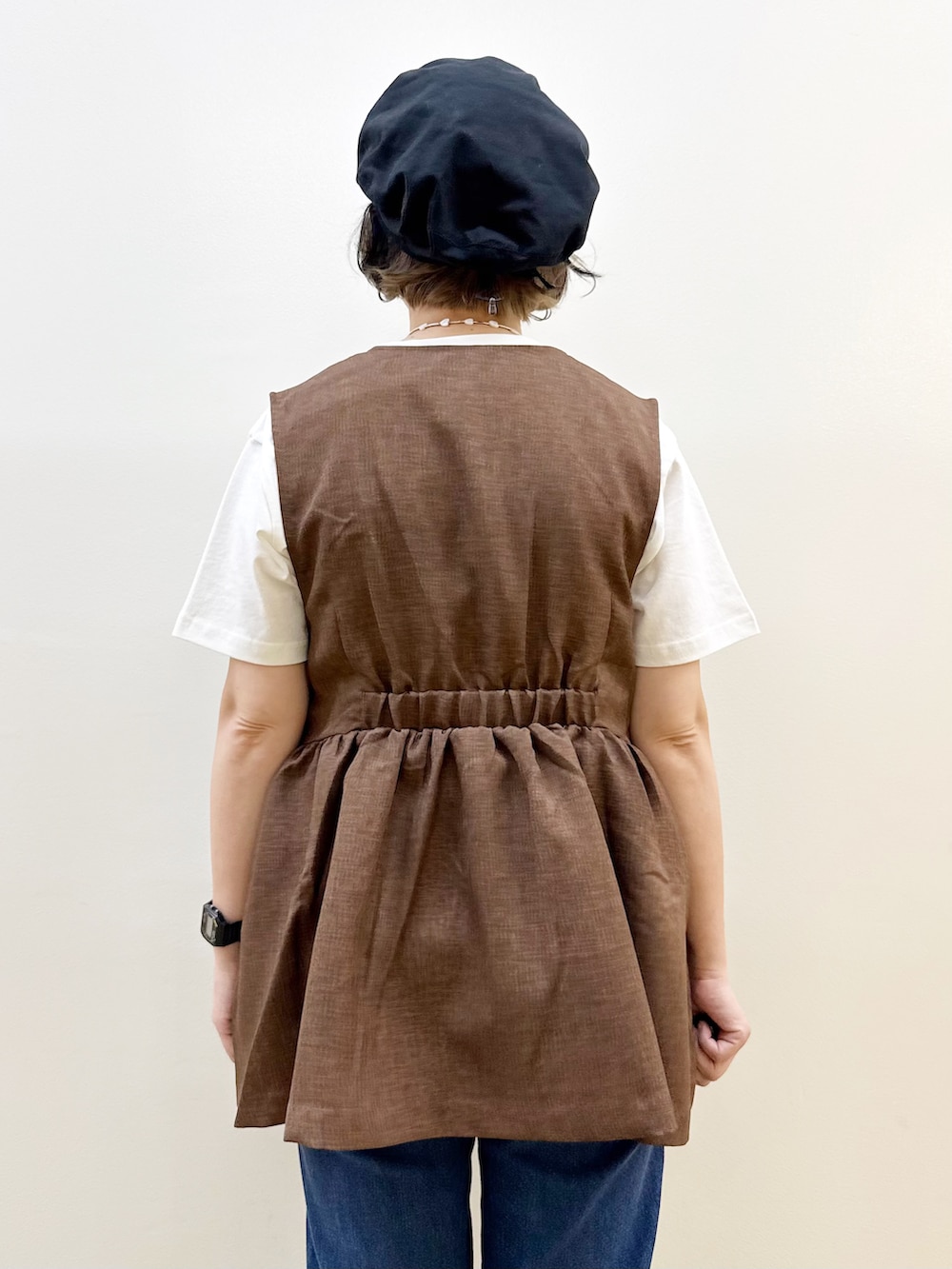 ブルー系のデニムパンツ、ホワイト系のTシャツ/カットソー、ブラウン系のベストを着用したレディースの夏コーディネートの6枚目の写真
