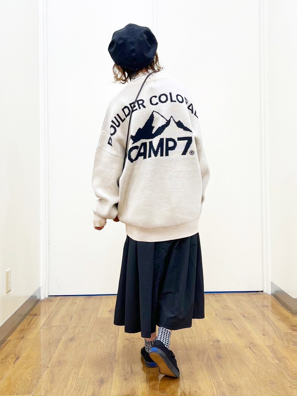 ホワイト系のニット/セーター、ホワイト系のTシャツ/カットソー、ブラック系のスカートを着用したレディースの秋コーディネートの3枚目の写真