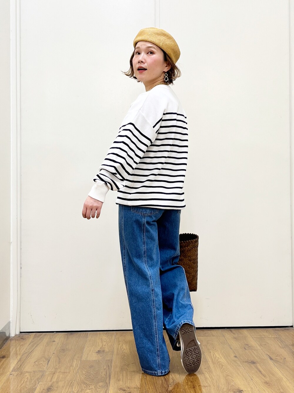 ブルー系のニット/セーター、ブルー系のデニムパンツ、ベージュ系のかごバッグを着用したレディースの春コーディネートの2枚目の写真