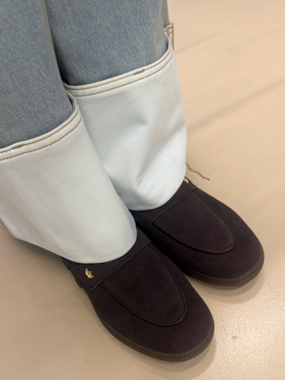 ブルー系のデニムパンツ、ブラウン系のスニーカー、ブラウン系のショルダーバッグを着用したレディースの春コーディネートの2枚目の写真