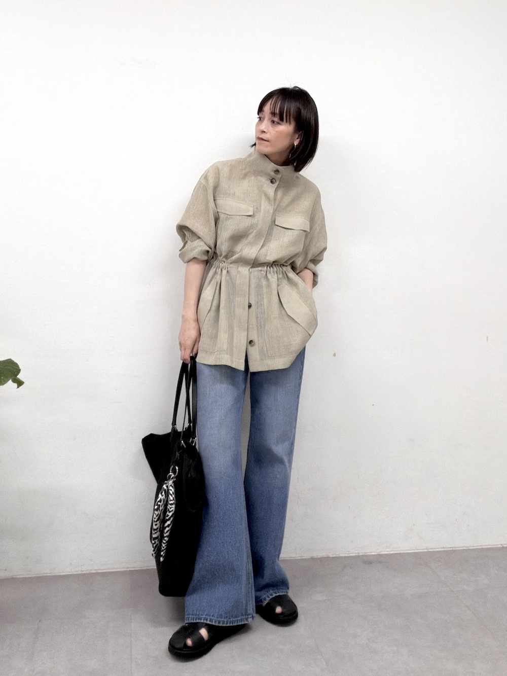 グリーン系のベスト、ブルー系のデニムパンツ、ブラック系のサンダルを着用したレディースの春コーディネートの4枚目の写真