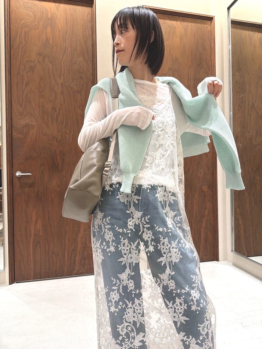 グリーン系のニット/セーター、ベージュ系のバックパック/リュック、ホワイト系のワンピースを着用したレディースの春コーディネートの3枚目の写真