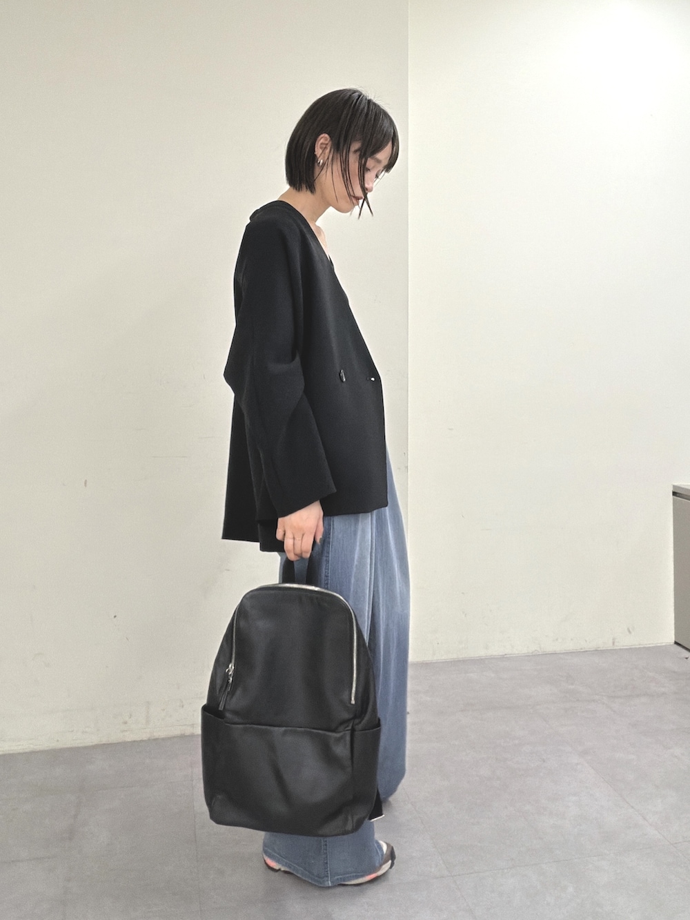 ブラック系のノーカラージャケット、ブラック系のニット/セーター、ブルー系のその他パンツを着用したレディースの春コーディネートの3枚目の写真