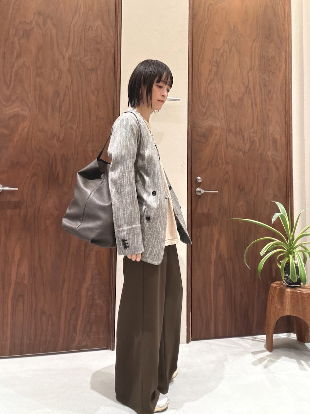 ブラック系のその他アウター、ベージュ系のTシャツ/カットソー、ブラウン系のショルダーバッグを着用したレディースの春コーディネートの2枚目の写真