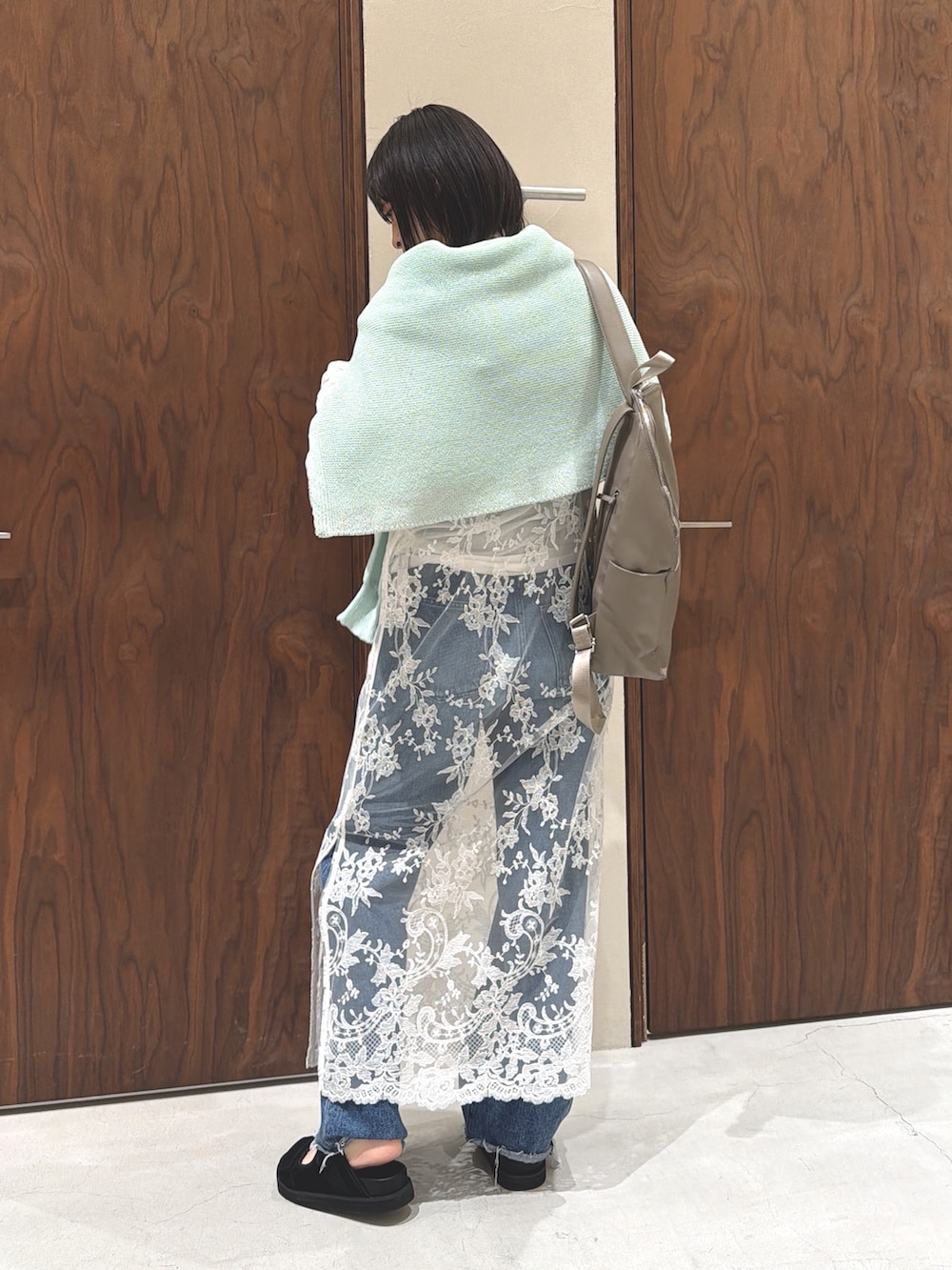 グリーン系のニット/セーター、ベージュ系のバックパック/リュック、ホワイト系のワンピースを着用したレディースの春コーディネートの5枚目の写真