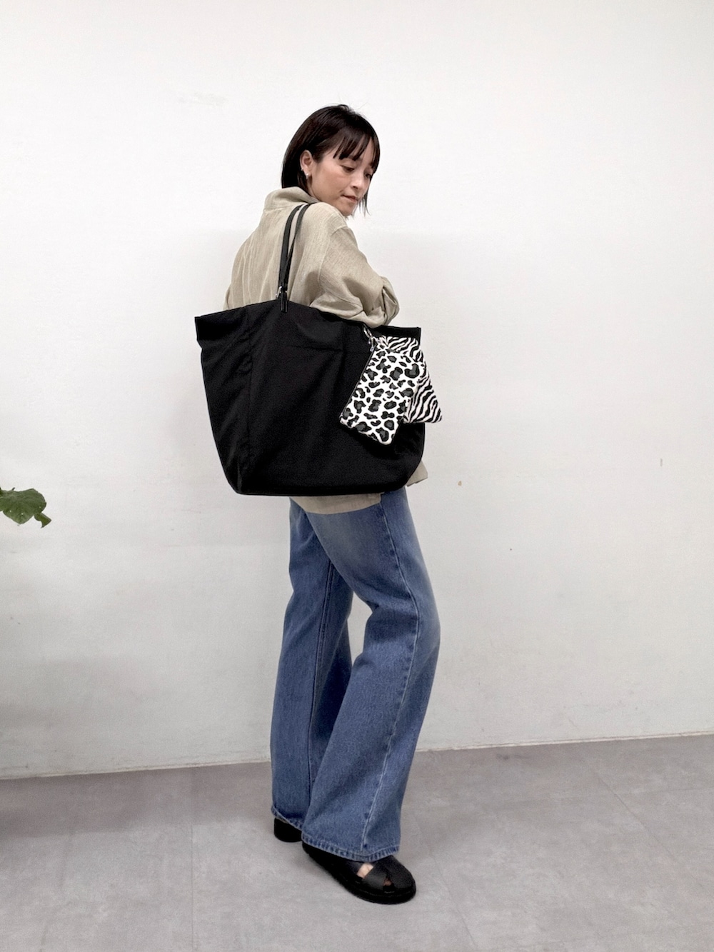 グリーン系のベスト、ブルー系のデニムパンツ、ブラック系のサンダルを着用したレディースの春コーディネートの2枚目の写真