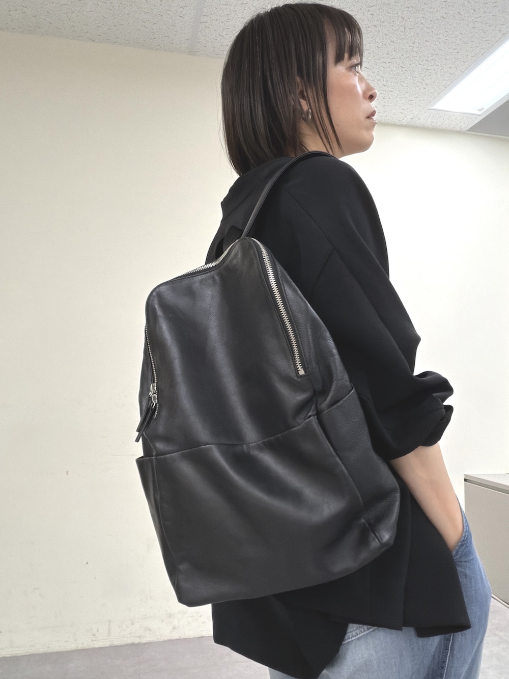 ブラック系のノーカラージャケット、ブラック系のニット/セーター、ブルー系のその他パンツを着用したレディースの春コーディネートの7枚目の写真