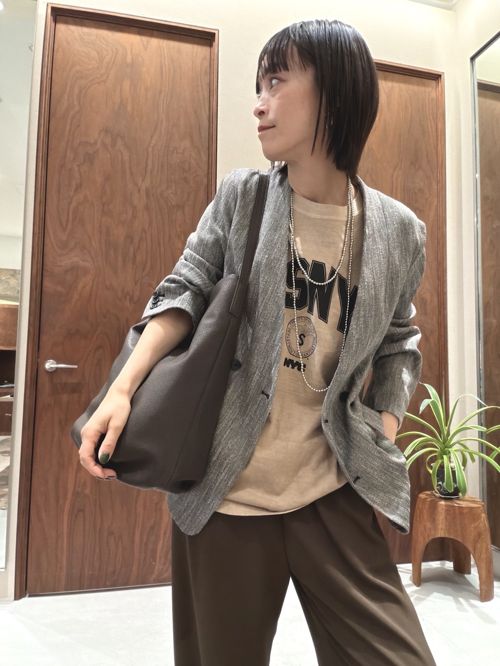 ブラック系のその他アウター、ベージュ系のTシャツ/カットソー、ブラウン系のショルダーバッグを着用したレディースの春コーディネートの5枚目の写真