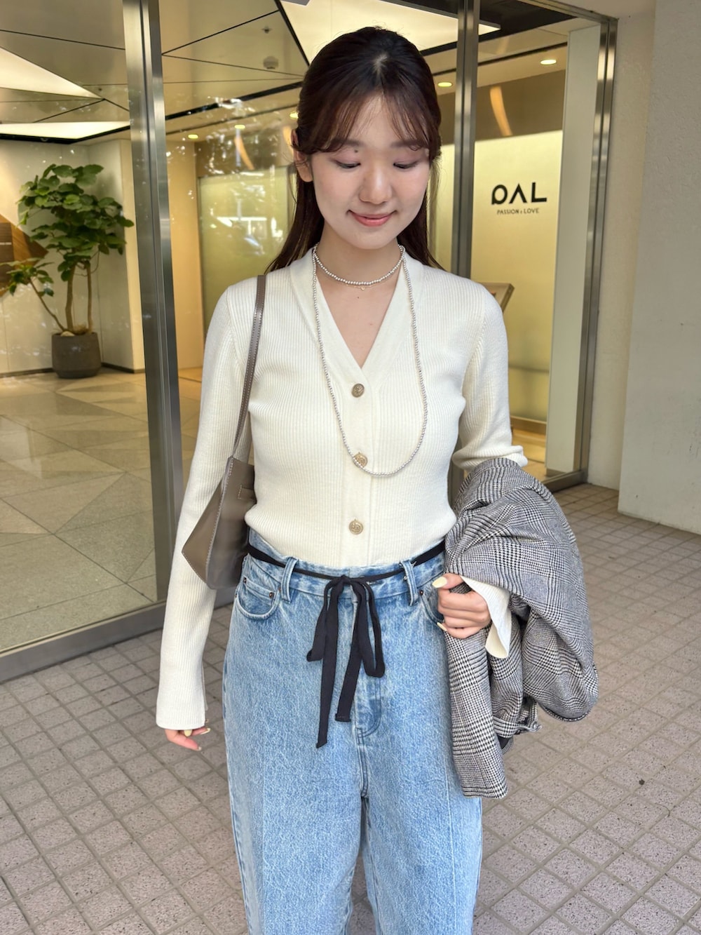 ブルー系のデニムパンツ、ブラウン系のパンプス、ブラウン系のショルダーバッグを着用したレディースの秋コーディネートの2枚目の写真