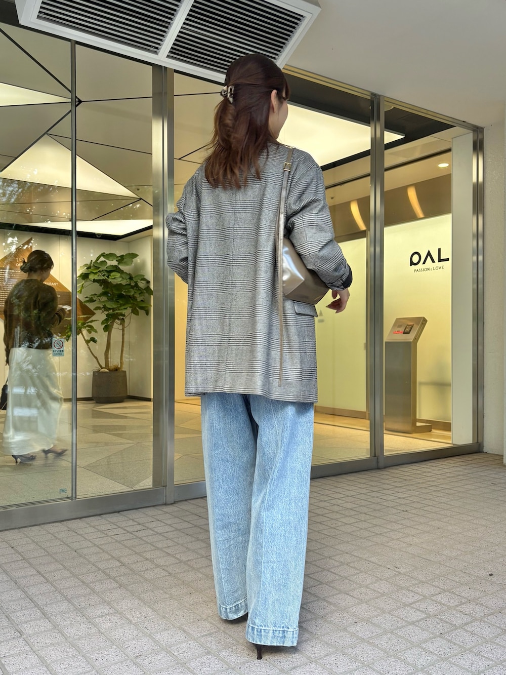 ブルー系のデニムパンツ、ブラウン系のパンプス、ブラウン系のショルダーバッグを着用したレディースの秋コーディネートの5枚目の写真