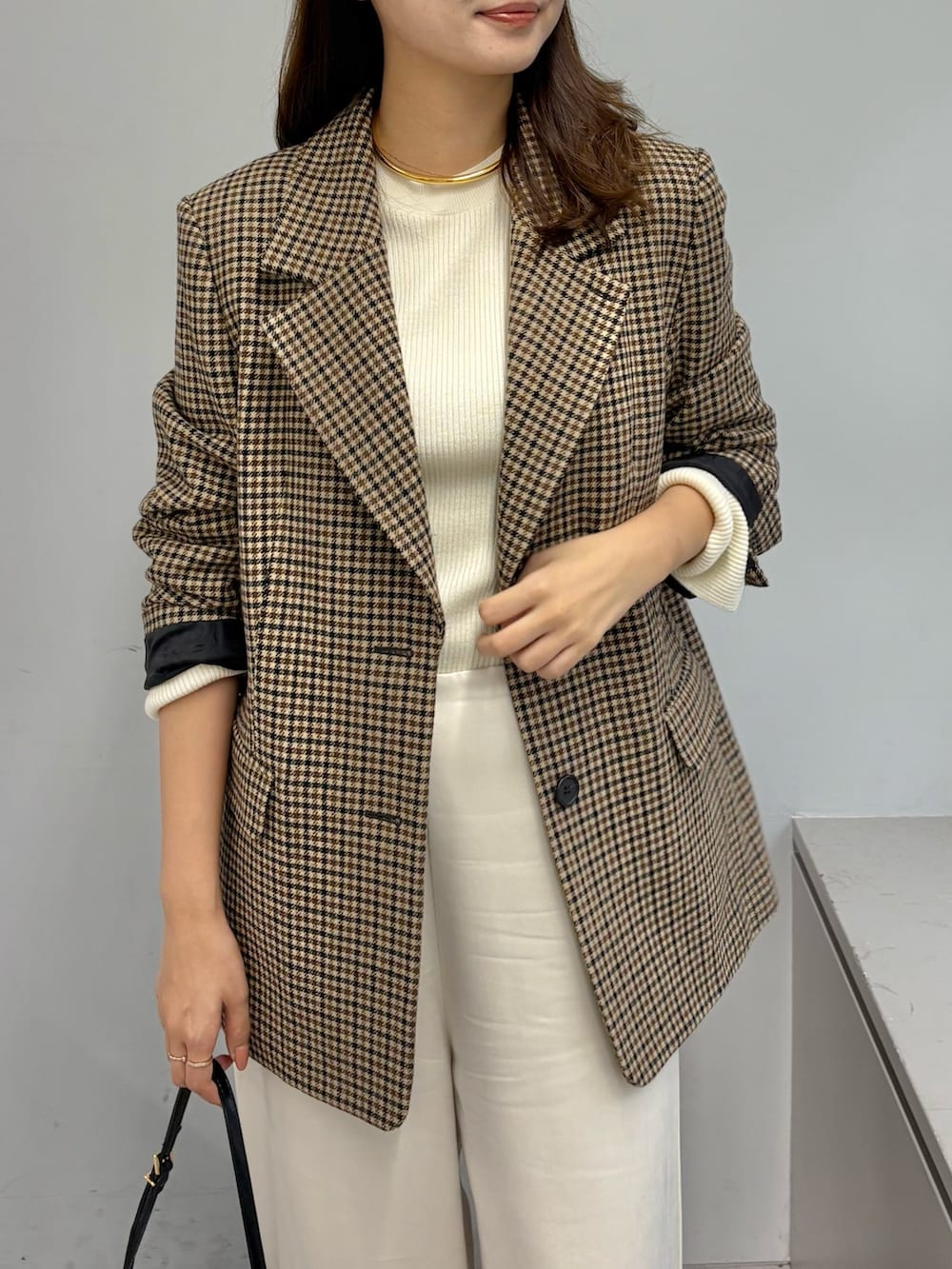 ブラウン系のテーラードジャケット、ホワイト系のニット/セーター、ホワイト系のその他パンツを着用したレディースの秋コーディネートの5枚目の写真