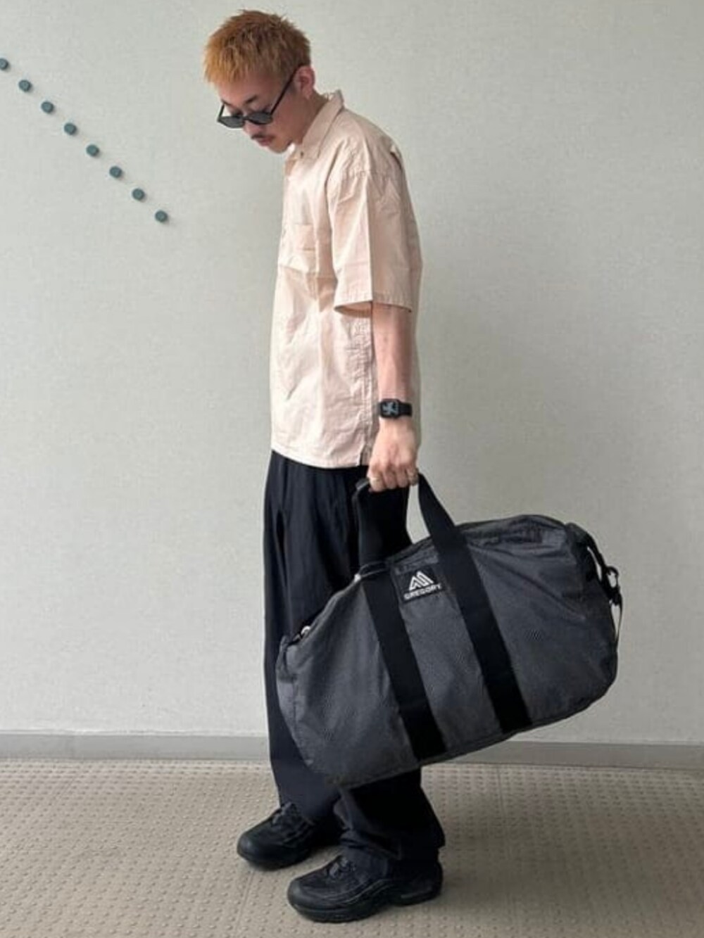 ブラック系のドラムバッグ、ピンク系のシャツ/ブラウス、ブラック系のスラックスを着用したメンズの春コーディネートの2枚目の写真