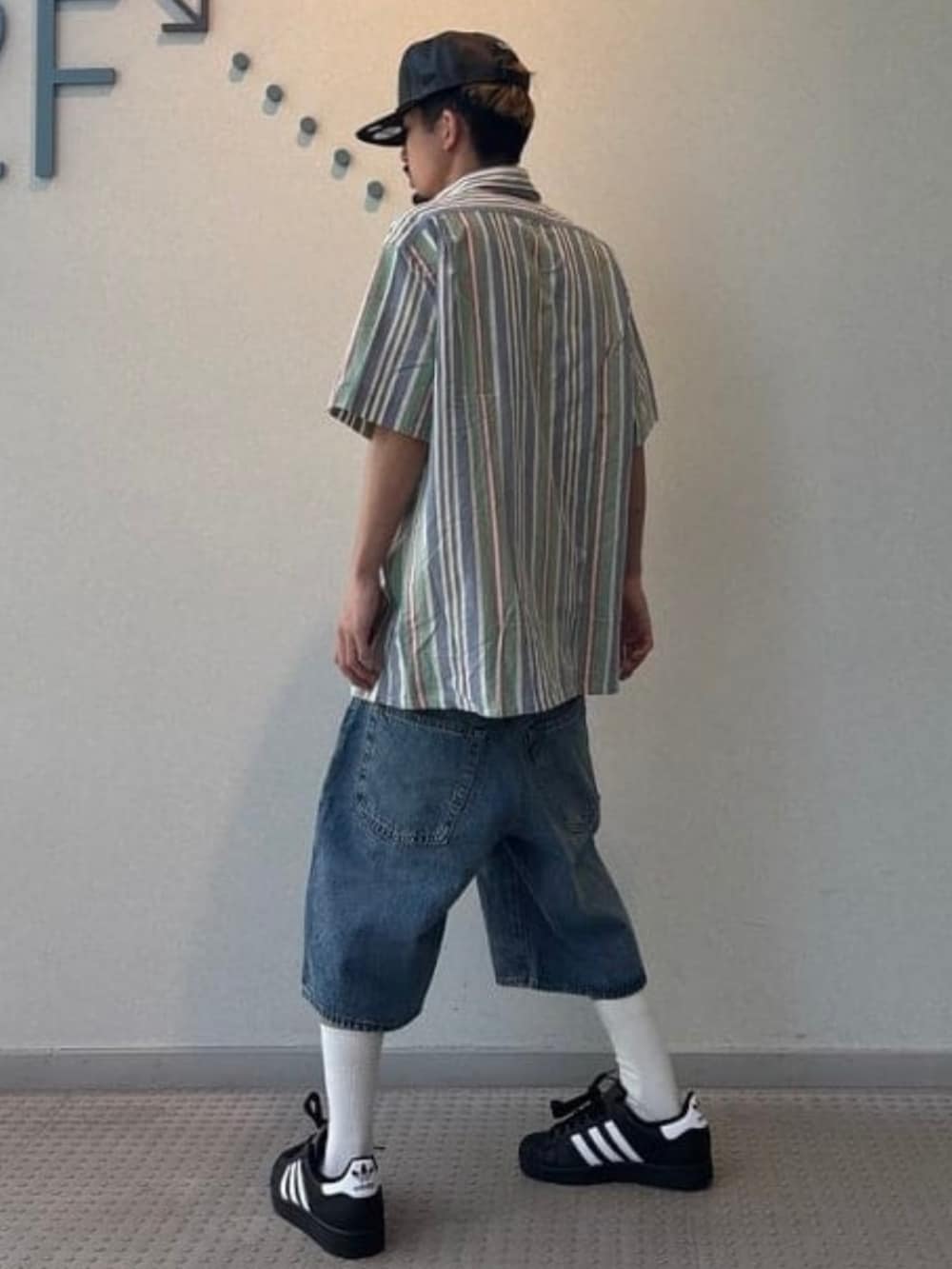 ブルー系のその他パンツ、ブラック系のスニーカー、ブラック系のキャップを着用したメンズの春コーディネートの2枚目の写真