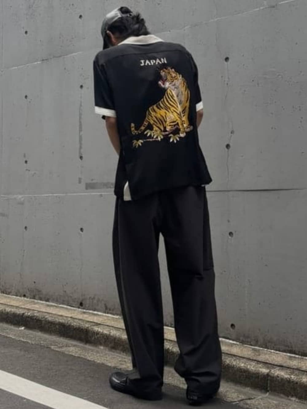 グレー系のスラックス、ブラック系のキャップを着用したメンズの夏コーディネートの3枚目の写真