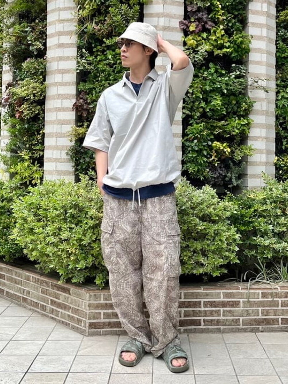 グレー系のポロシャツ、ベージュ系のカーゴパンツ、グリーン系のサンダルを着用したメンズの夏コーディネートの2枚目の写真