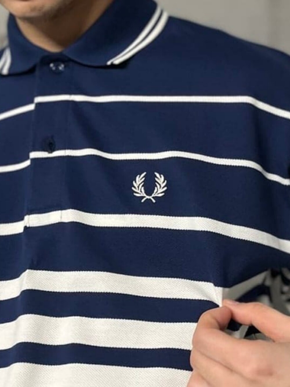 グレー系のスラックス、ブルー系のポロシャツ、ホワイト系のスニーカーを着用したメンズの春コーディネートの3枚目の写真