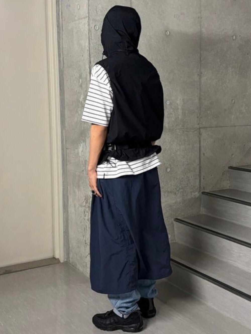 ホワイト系のTシャツ/カットソー、ブラック系のベスト、ブルー系のデニムパンツを着用したメンズの春コーディネートの2枚目の写真