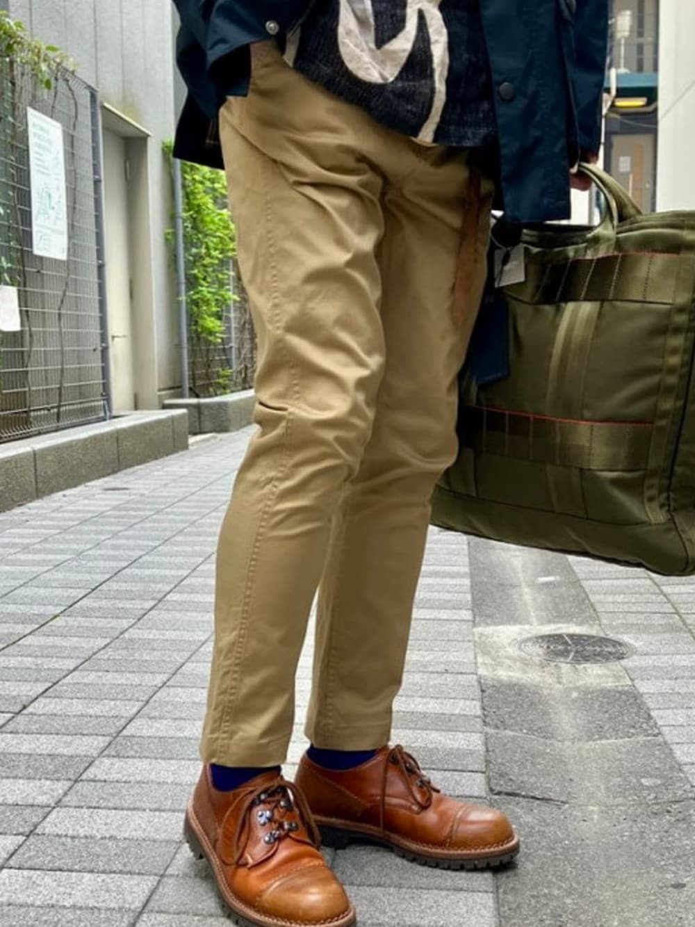 ベージュ系のチノパンツ、ブラック系のブルゾン、ブルー系のハットを着用したメンズの春コーディネートの2枚目の写真
