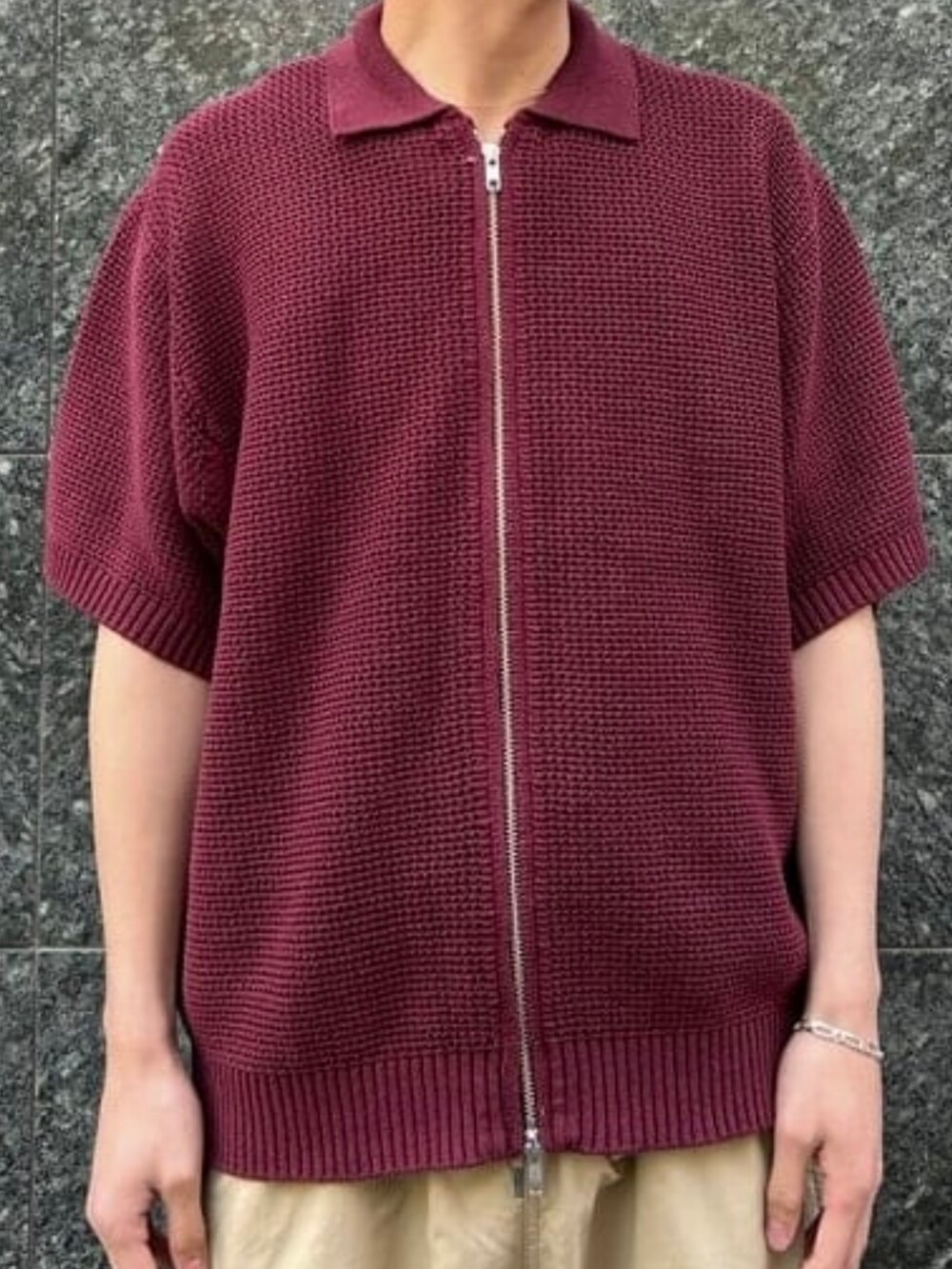 レッド系のポロシャツ、シルバー系のブレスレットを着用したメンズの春コーディネートの3枚目の写真