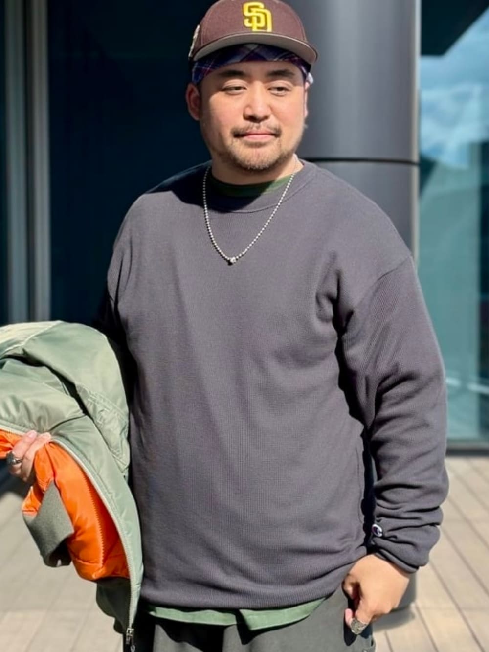 グリーン系のMA-1、ブラック系のTシャツ/カットソー、ブラック系のスウェットパンツを着用したメンズの夏コーディネートの3枚目の写真
