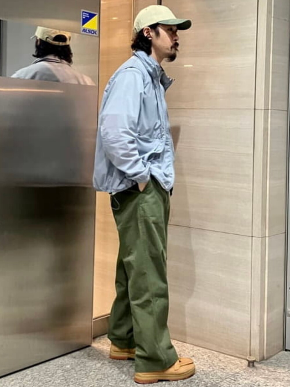 グレー系のブルゾン、グレー系のベスト、ブラウン系のキャップを着用したメンズの春コーディネートの2枚目の写真