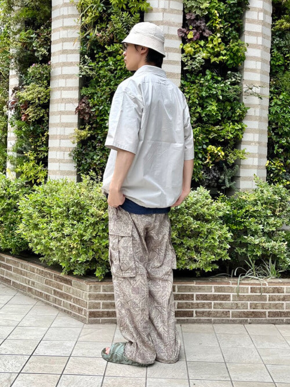 グレー系のポロシャツ、ベージュ系のカーゴパンツ、グリーン系のサンダルを着用したメンズの夏コーディネートの3枚目の写真