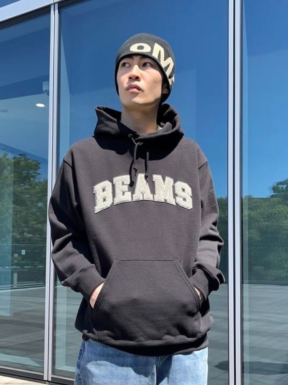 ブラック系のパーカー、ブルー系のデニムパンツ、ブラック系のスニーカーを着用したメンズの秋コーディネートの2枚目の写真