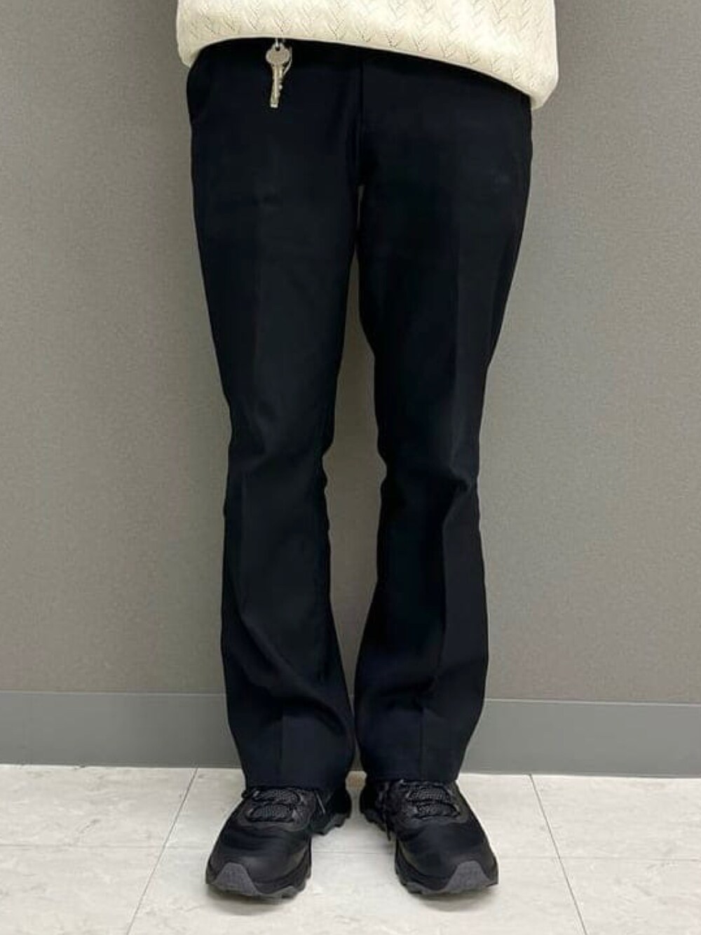 ホワイト系のポロシャツ、ブラック系のスラックス、ブラック系のスニーカーを着用したメンズの夏コーディネートの5枚目の写真