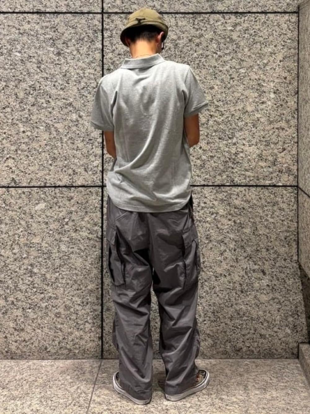 グレー系のカーゴパンツ、グレー系のポロシャツ、グリーン系のハットを着用したメンズの夏コーディネートの2枚目の写真