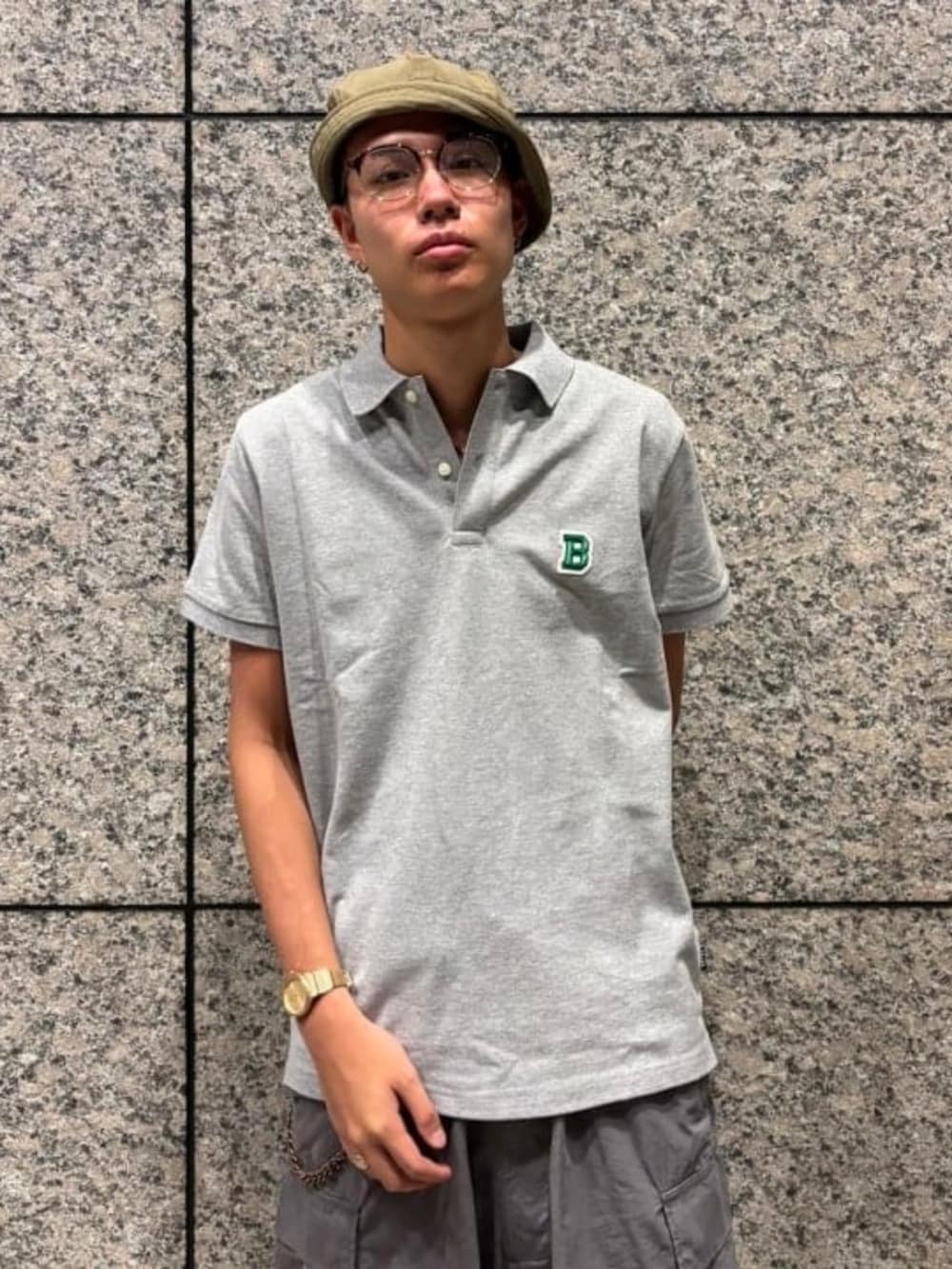 グレー系のカーゴパンツ、グレー系のポロシャツ、グリーン系のハットを着用したメンズの夏コーディネートの3枚目の写真