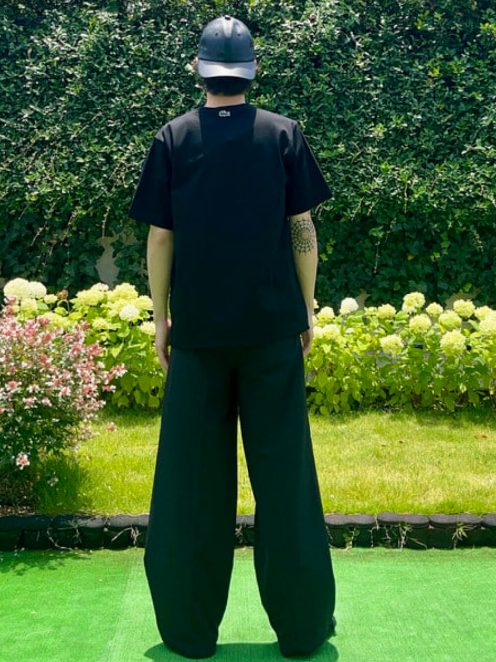 ブラック系のTシャツ/カットソー、ブラック系のサンダル、ブラック系のキャップを着用したメンズの夏コーディネートの3枚目の写真