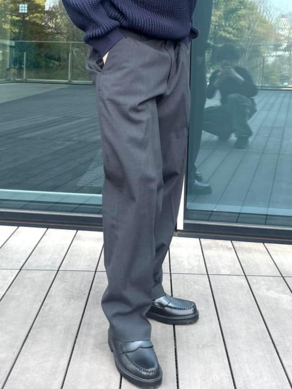 グレー系のスラックス、ブラック系のレインシューズ、ブルー系のニット/セーターを着用したメンズの春コーディネートの3枚目の写真