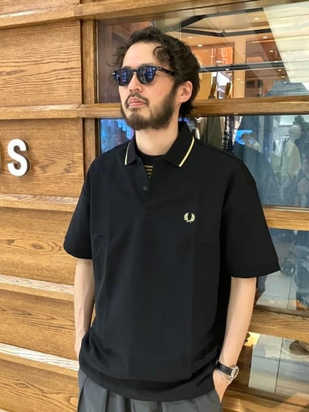 ブラック系のポロシャツ、ブラック系のTシャツ/カットソー、グレー系のスラックスを着用したメンズの夏コーディネートの4枚目の写真