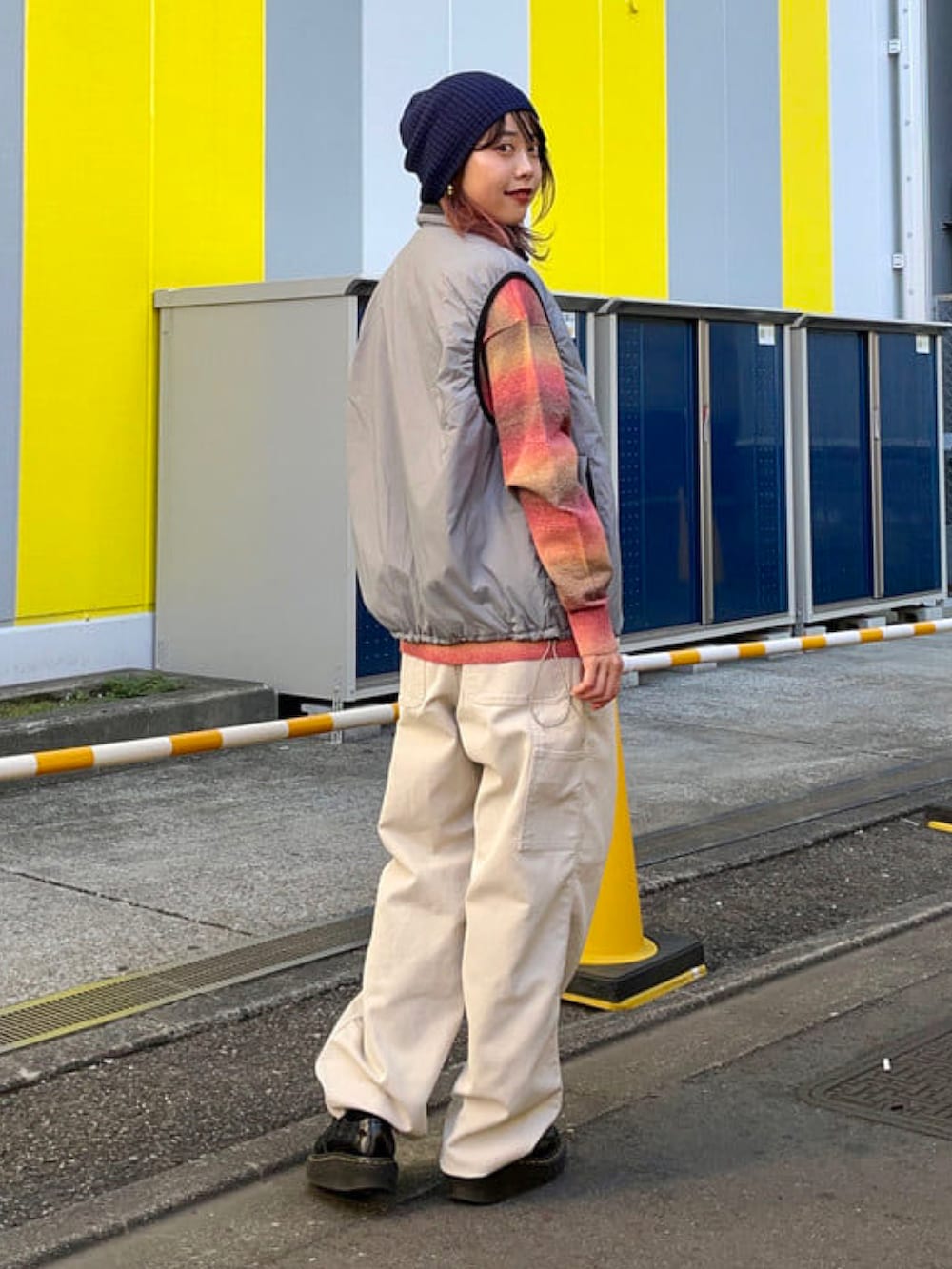 レッド系のニット/セーター、グレー系のベスト、グレー系のその他パンツを着用したレディースの秋コーディネートの2枚目の写真