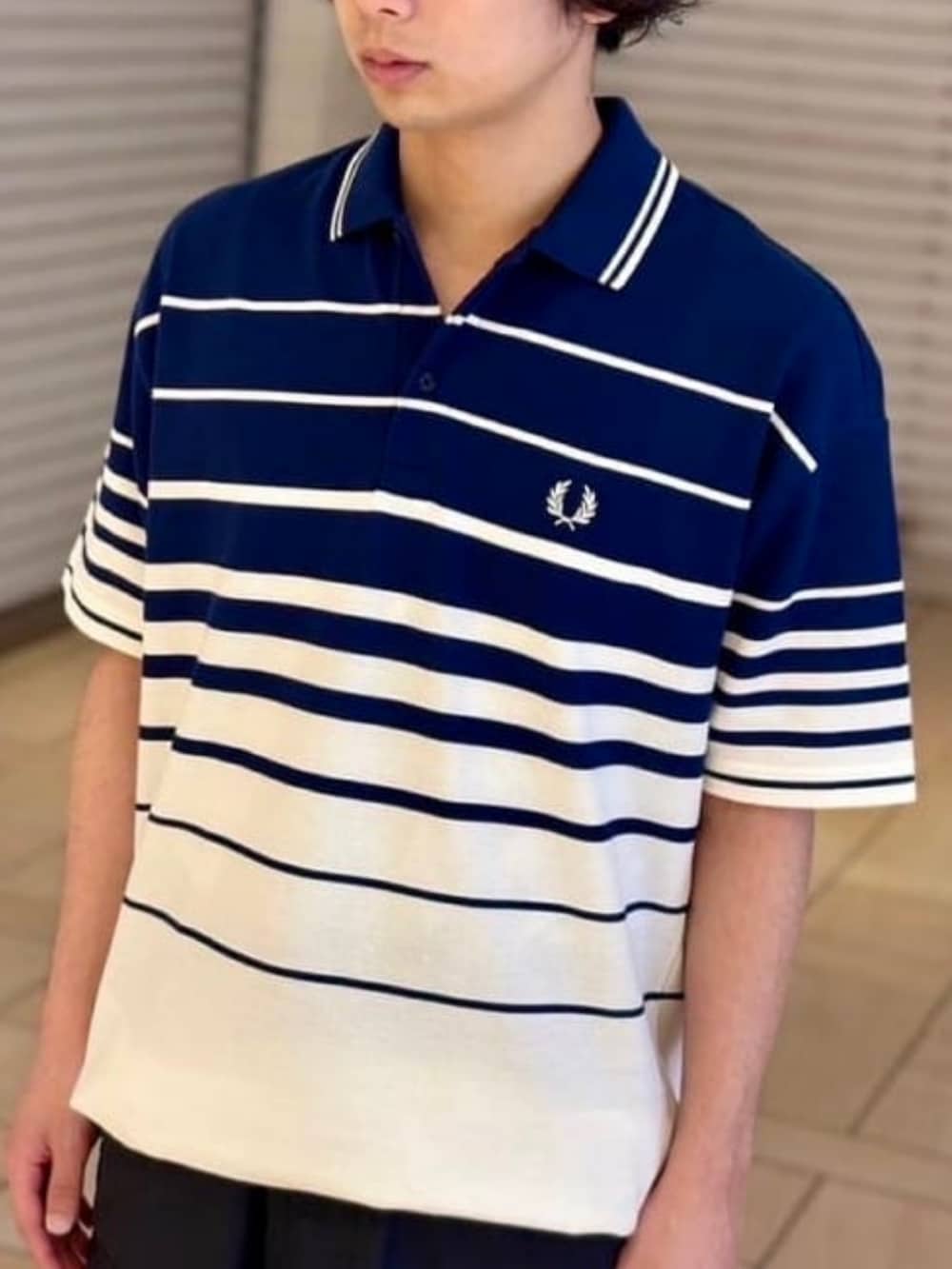 ブラック系のカーゴパンツ、ブルー系のポロシャツを着用したメンズの春コーディネートの2枚目の写真