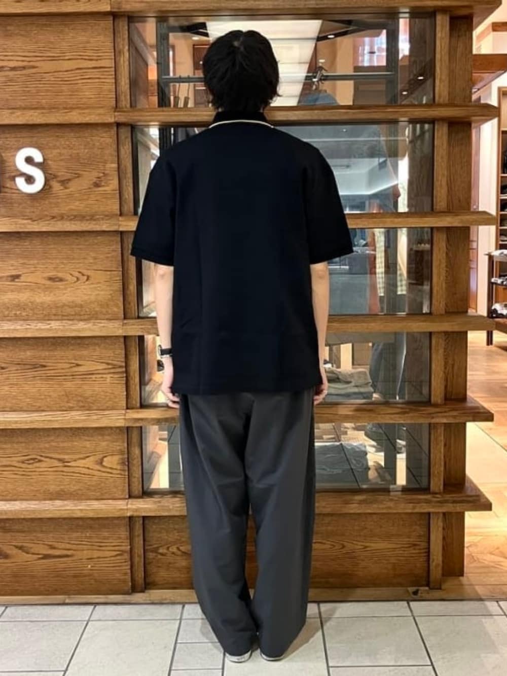 ブラック系のポロシャツ、ブラック系のTシャツ/カットソー、グレー系のスラックスを着用したメンズの夏コーディネートの3枚目の写真