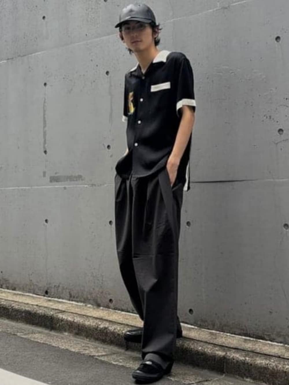 グレー系のスラックス、ブラック系のキャップを着用したメンズの夏コーディネートの2枚目の写真