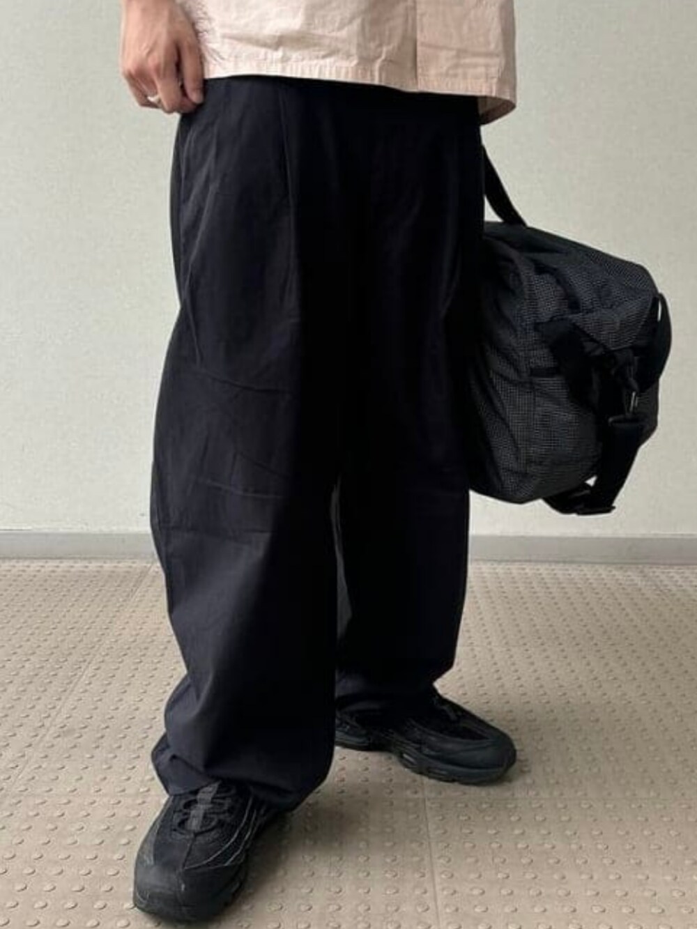 ブラック系のドラムバッグ、ピンク系のシャツ/ブラウス、ブラック系のスラックスを着用したメンズの春コーディネートの5枚目の写真