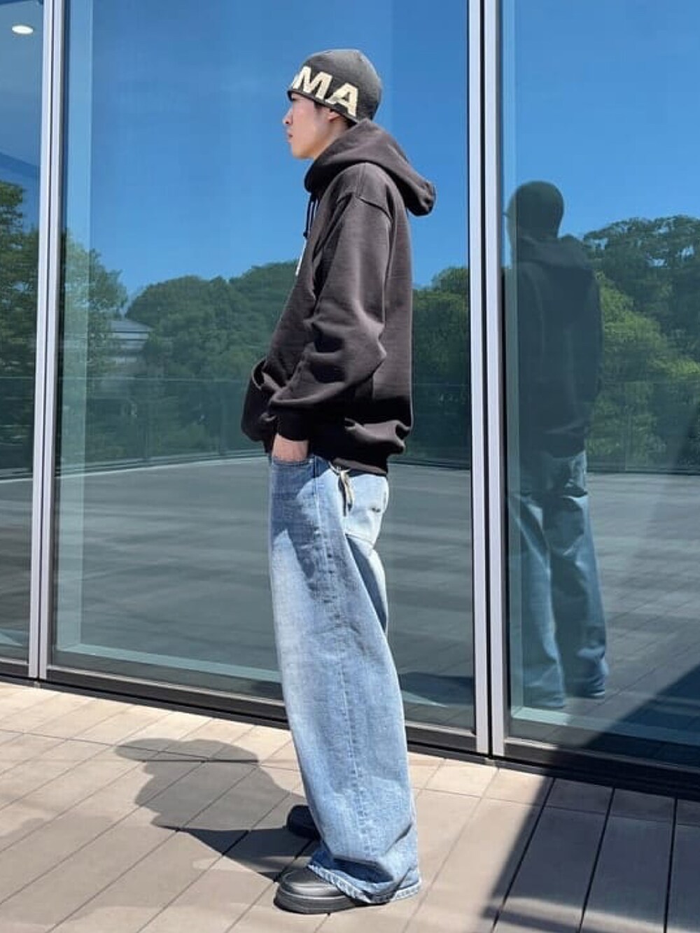 ブラック系のパーカー、ブルー系のデニムパンツ、ブラック系のスニーカーを着用したメンズの秋コーディネートの4枚目の写真