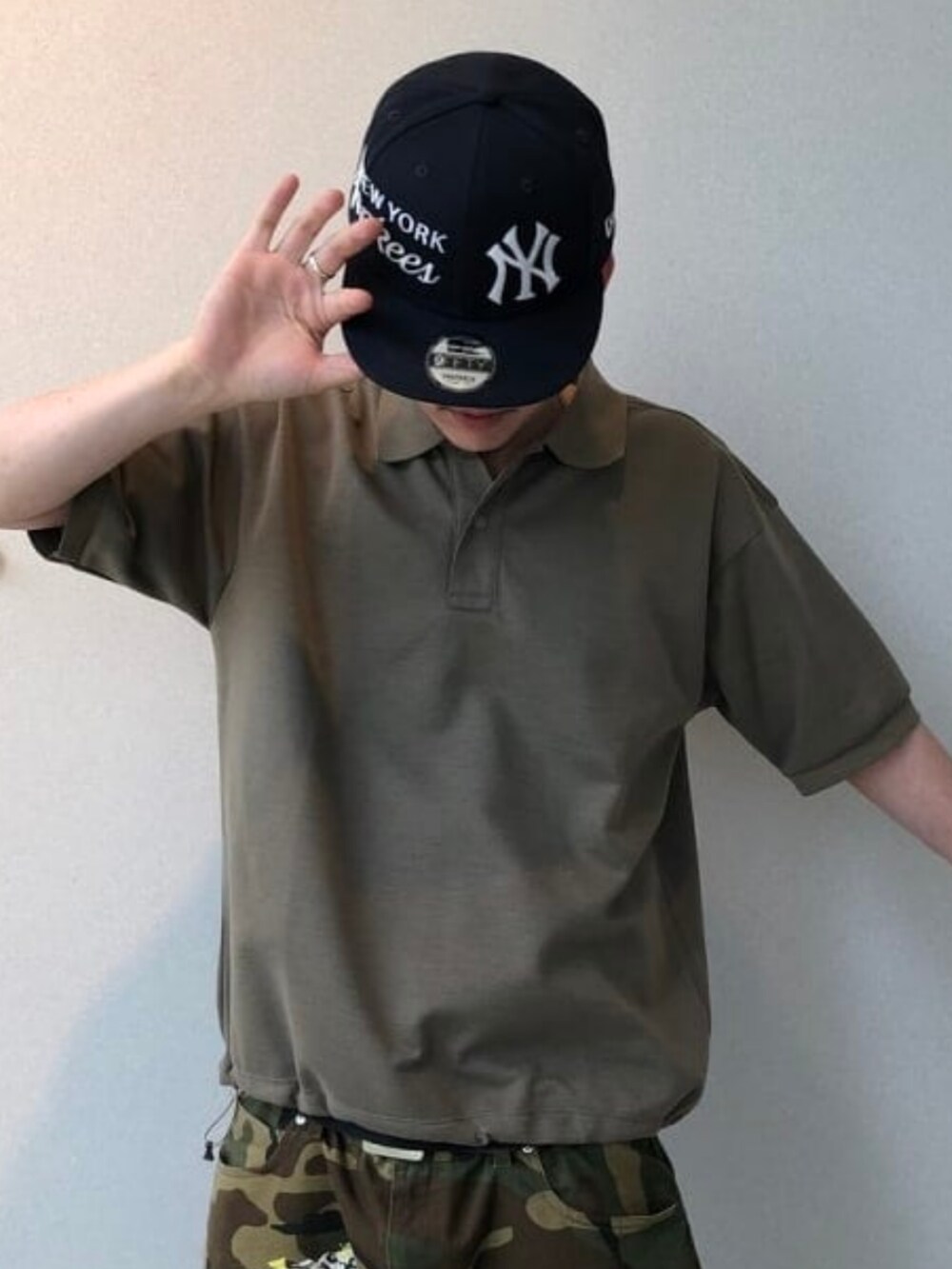 ベージュ系のポロシャツ、グレー系のスニーカー、ブルー系のキャップを着用したメンズの夏コーディネートの3枚目の写真