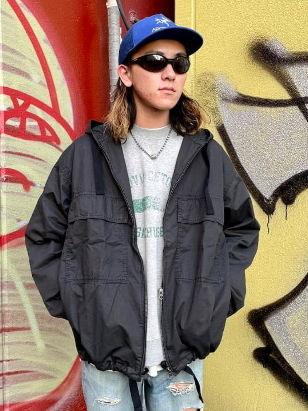 ブラック系のミリタリージャケット、ブルー系のデニムパンツ、グレー系のスウェットを着用したメンズの春コーディネートの3枚目の写真