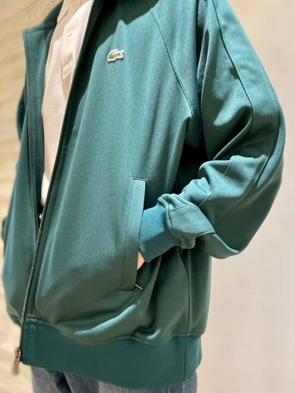 ホワイト系のポロシャツ、グリーン系のジャージ、ブルー系のデニムパンツを着用したメンズの春コーディネートの3枚目の写真