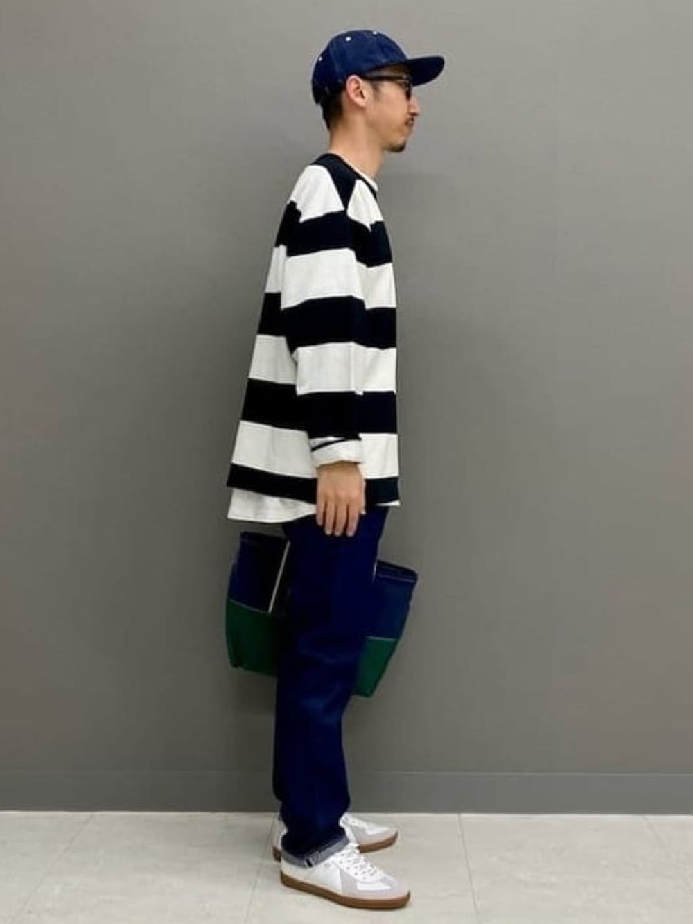 ブラック系のTシャツ/カットソー、ブルー系のデニムパンツ、ホワイト系のスニーカーを着用したメンズの春コーディネートの4枚目の写真