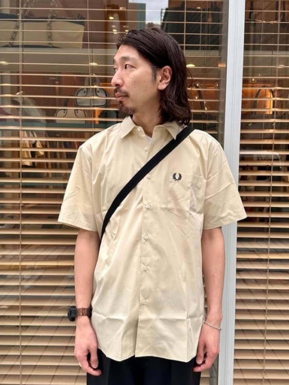 ブラック系のスラックス、ベージュ系のシャツ/ブラウス、ブラック系のショルダーバッグを着用したメンズの夏コーディネートの2枚目の写真